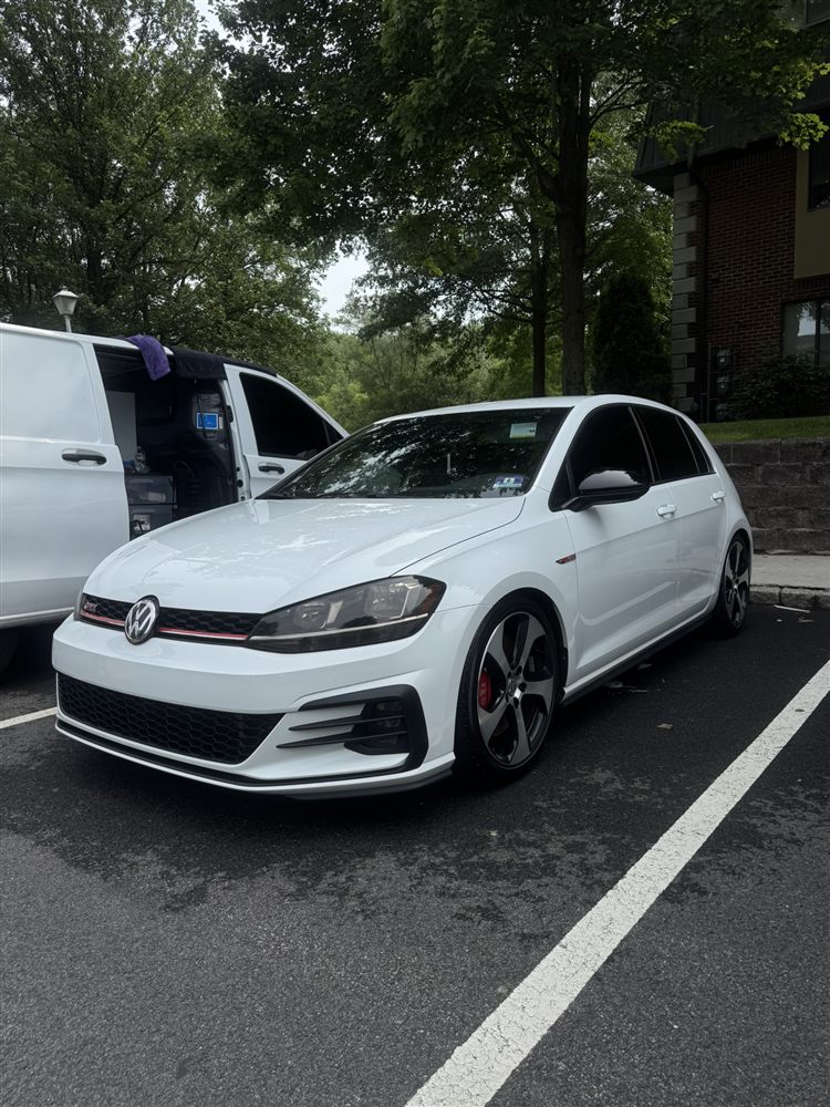 Freshly washed white VW Golf GTI, Rev Up detailing van in background