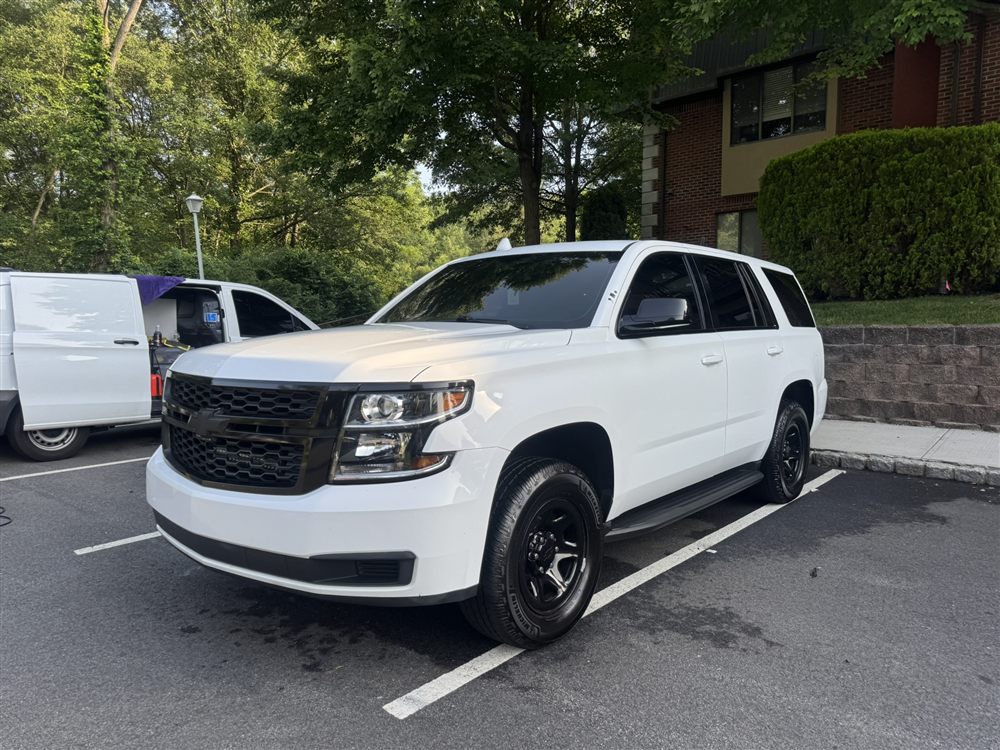 Freshly washed white Chevy Tahoe, Rev Up detailing van in background