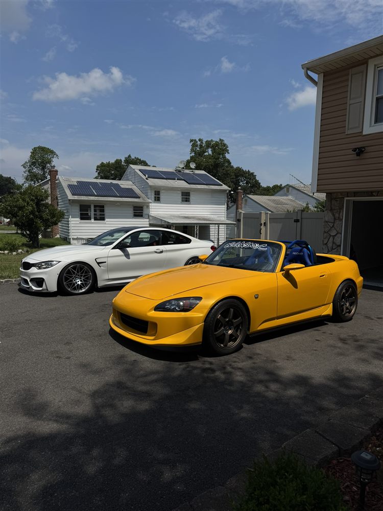 Freshly washed white BMW M4 and yellow Honda S2000 side by side